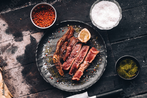 Succulent Farmhouse Rustic Rump Steak with thyme garnish shot against a dark background with wood burner. The perfect image for your bistro or restaurant menu cover art. Copy space.