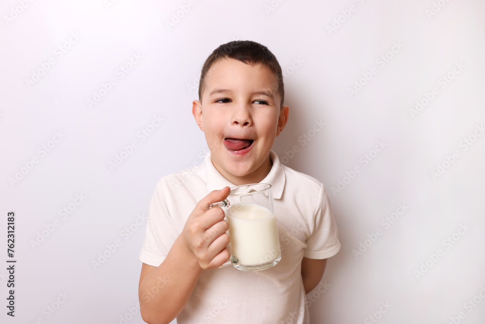 The boy licks himself after tasting the delicious milk. Children's healthy food. The boy licks himself after tasting the delicious milk. Children's healthy food.