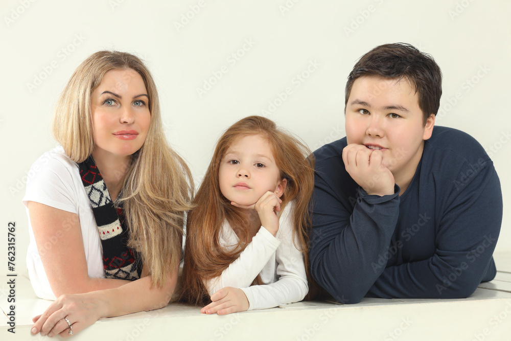 Family (mother, daughter and son) are on white floor in white studio Family (mother, daughter and son) are on white floor in white studio