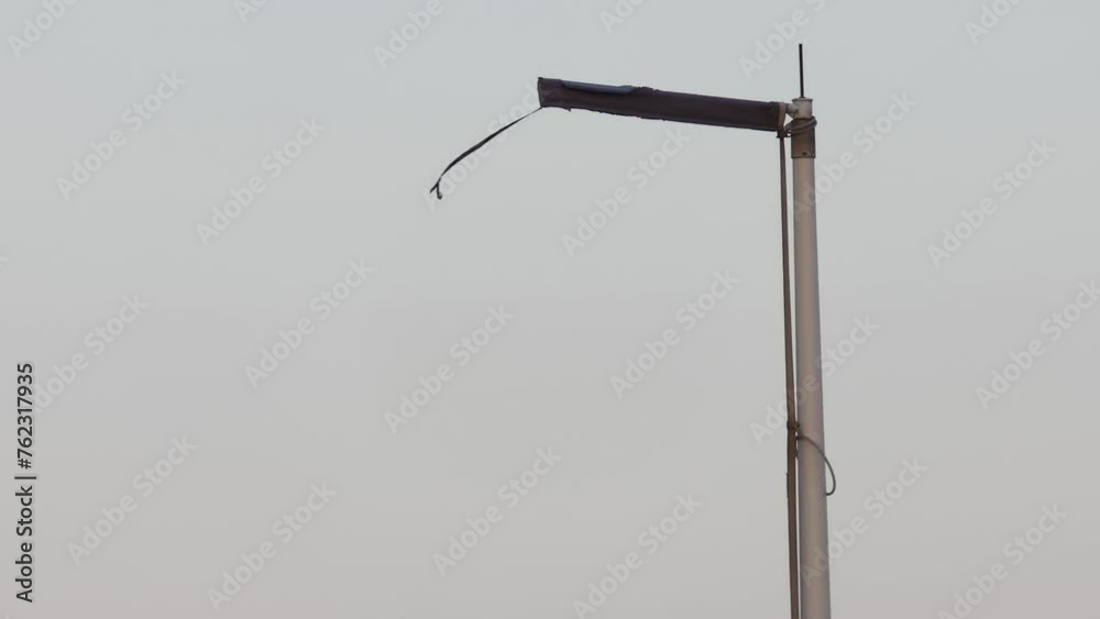 The flagpole without flag is swinging in the wind. The flagpole without flag is swinging in the wind.