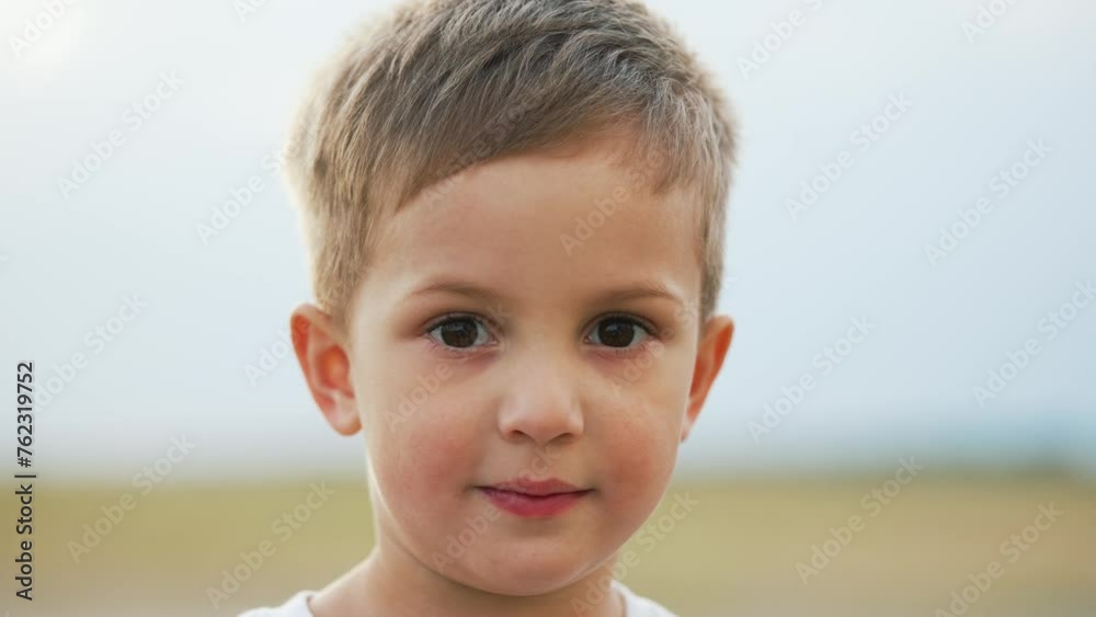 Portrait of a child. Cheerful happy kid boy in summer park at sunset. Dream kid child look into the camera on nature in the park. Toddler child playing outdoors on green grass portrait. Happy child Portrait of a child. Cheerful happy kid boy in summer park at sunset. Dream kid child look into the camera on nature in the park. Toddler child playing outdoors on green grass portrait. Happy child