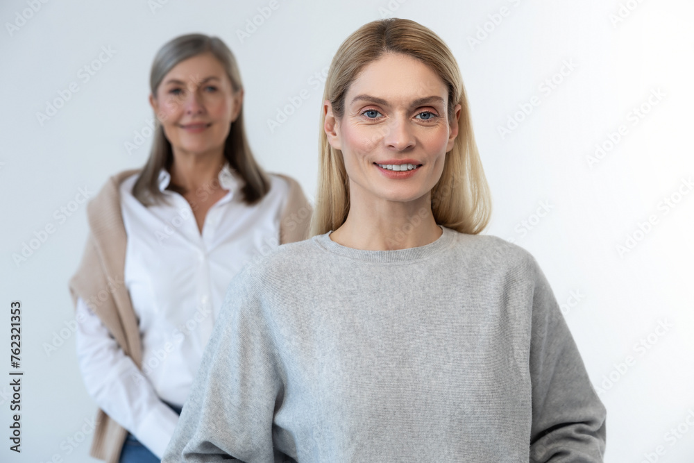 Blonde long-haired woman standing, her mom standing behind Blonde long-haired woman standing, her mom standing behind