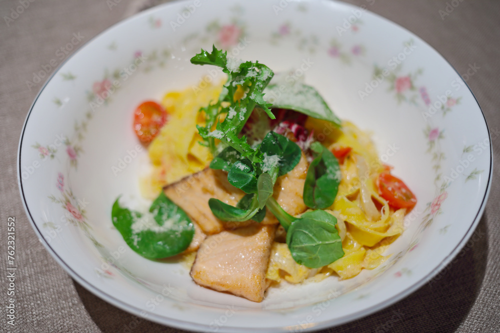 Fish with vegetables, pasta on plate on table in restaurant, close-up Fish with vegetables, pasta on plate on table in restaurant, close-up