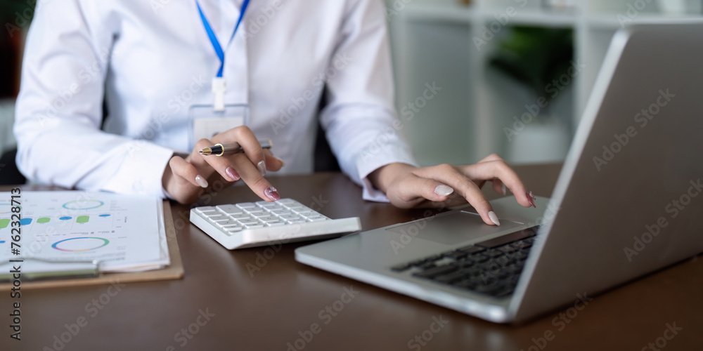 Finance concept. Close up businesswoman hold a graph pen and writing report, and memo, and analyzing business documents with a laptop computer Finance concept. Close up businesswoman hold a graph pen and writing report, and memo, and analyzing business documents with a laptop computer