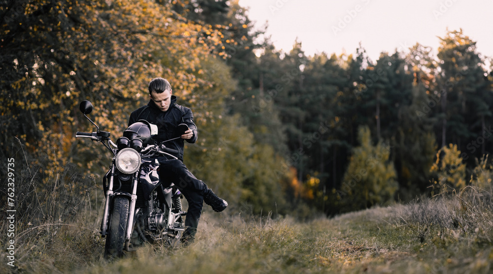 male motorcyclist in nature with a custom classic motorcycle. Stylish male biker