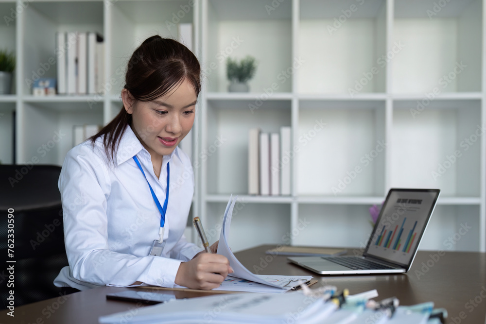 Asian business woman using laptop to analysis graph financial budget report and planning for future in office desk Asian business woman using laptop to analysis graph financial budget report and planning for future in office desk
