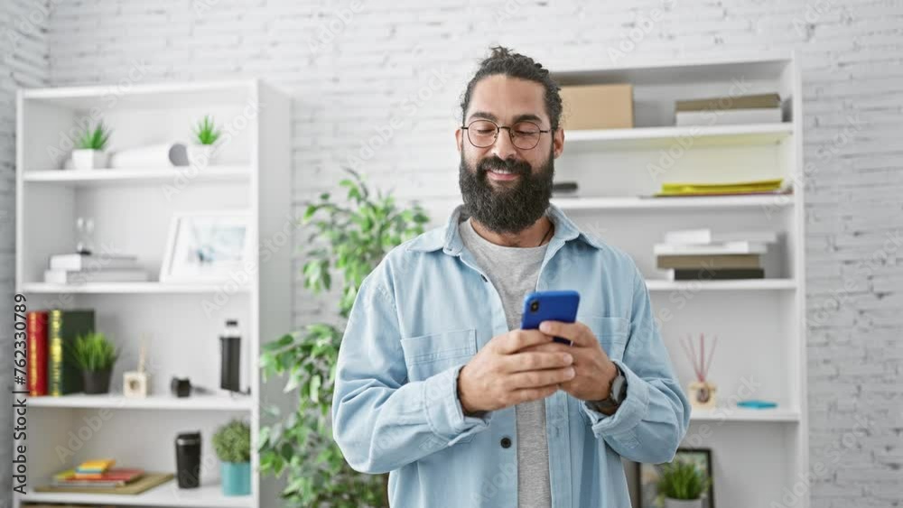 Smiling bearded man using smartphone in modern office, reflecting contemporary workplace trends and technology use Smiling bearded man using smartphone in modern office, reflecting contemporary workplace trends and technology use