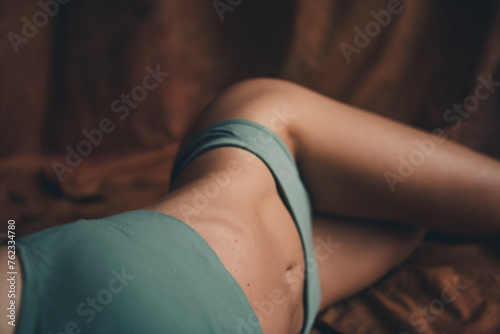 Photo of perfect model young female in khaki top and panties laying down slim body stomach hips isolated over brown textile background