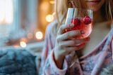  Young woman holds in hand glass Sleepy girl Cocktail on the background of a cozy bedroom. A drink with magnesium to improve the quality of sleep. 
