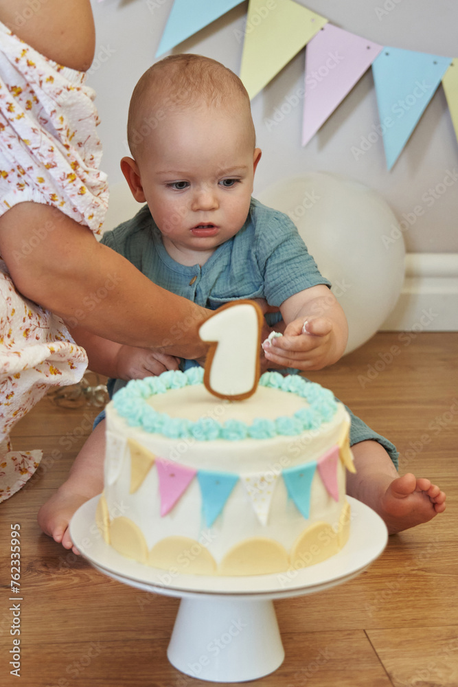 With a joyful glint in his eyes, the one-year-old birthday boy smashes his tiny fists into his cake, the brightly colored frosting creating an adorable mess on his face and hands.