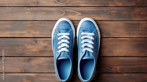 Blue sneakers resting on a wooden surface, suitable for sports or lifestyle themes