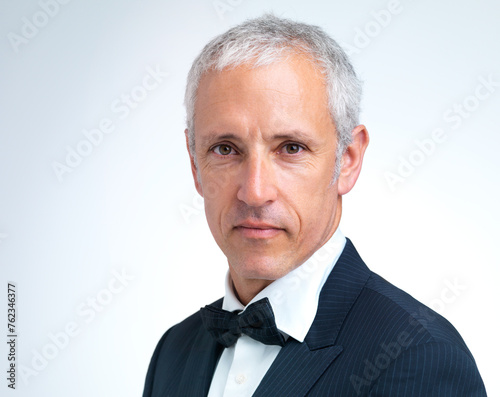 Portrait, mature man and tuxedo in studio with confidence, designer fashion and stylish in white background. Serious, elegant and male person with pride in suit, fancy and cool style in mockup space