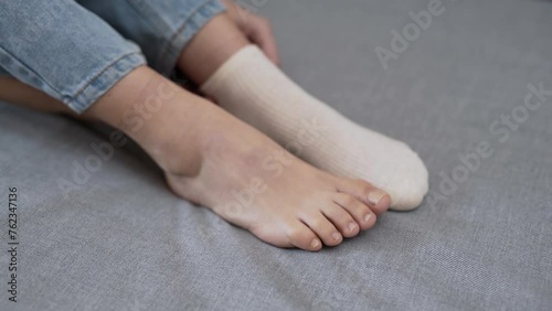 Close-up of girl's feet taking off white socks. He takes his socks off.