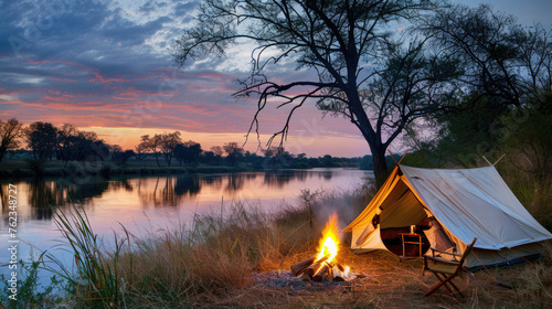 Camping tent in a camping on the river bank with a cozy fire