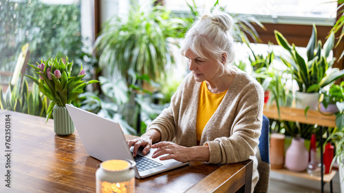 Mature woman using laptop while sitting at the table at home
