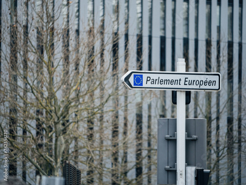 Street signage directs to the European Parliament, with office buildings in the background.