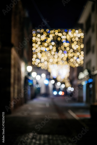 A bokeh effect of festive lights hanging above a quiet urban street at night