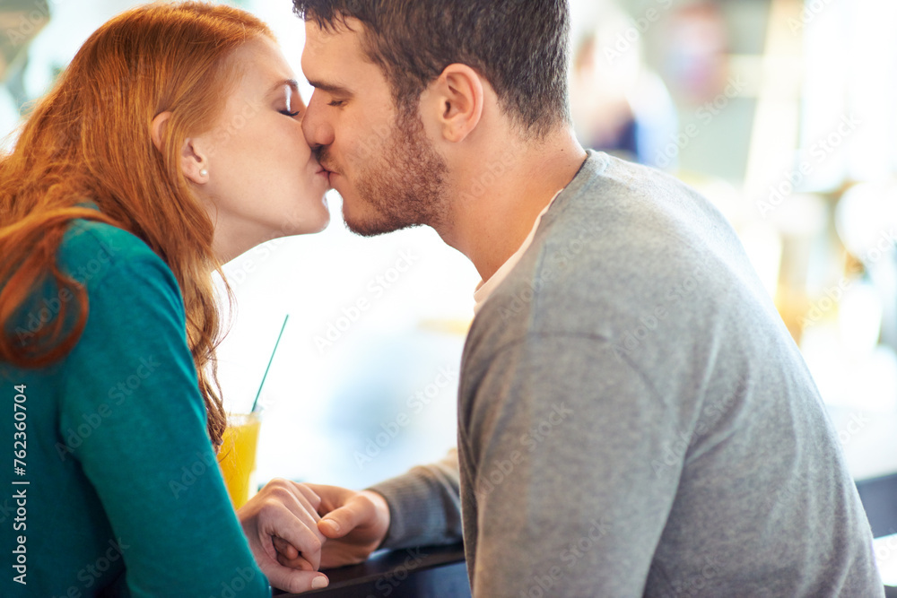 Couple, date and kiss with romance, coffee shop or restaurant with happiness together. Man, woman and love for relationship, care and smile for flirting on break for relax or bonding in cafe - obrazy, fototapety, plakaty 