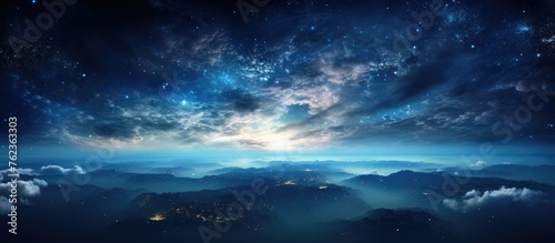 A stunning natural landscape at night, with a sky full of stars and majestic mountains in the foreground. Cumulus clouds drift across the horizon, adding to the peaceful atmosphere of the scene