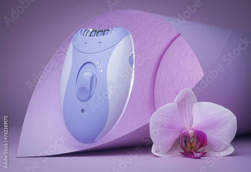 Modern epilator on purple background. skin care, removal of unwanted hair.