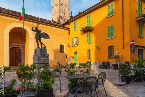 Cafe tables and chairs outside in old cozy street in medieval town square on Como lake in outdoor restaurant with nobody, Lenno comune, Lombardy, Italy. Popular travel and tourist destination