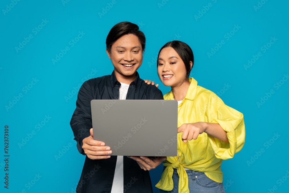 Enthusiastic Asian couple collaboratively working on a laptop with attentive and joyful expressions Enthusiastic Asian couple collaboratively working on a laptop with attentive and joyful expressions