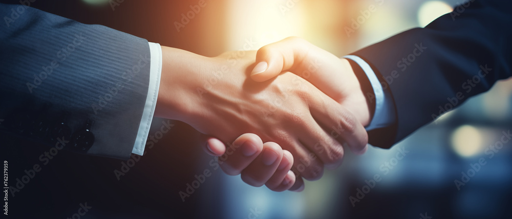 Close up at hands of two young business people shaking hands with sun beam on background. Close up at hands of two young business people shaking hands with sun beam on background.