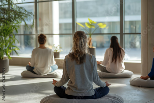 wellness yoga meditation concept  A group of women are sitting on pillows in a room  meditating. The room is filled with plants and has a calming atmosphere