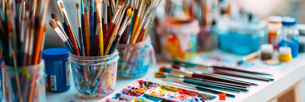 A collection of colorful art supplies neatly arranged on a white table, including paintbrushes, watercolor paints, and sketchbooks A collection of colorful art supplies neatly arranged on a white table, including paintbrushes, watercolor paints, and sketchbooks