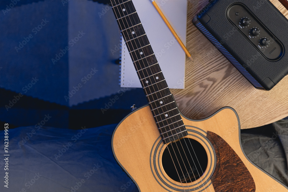 Fototapeta premium Musical background with acoustic guitar, speaker and notepad on the table.