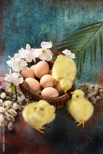 Easter background with a wicker basket full of eggs and yellow chickens