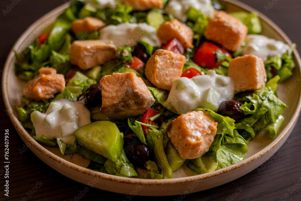 Close-up of a delicious Mediterranean salad featuring pieces of salmon fillet and a dollop of tzatziki sauce, offering a fresh and flavorful dining experience Close-up of a delicious Mediterranean salad featuring pieces of salmon fillet and a dollop of tzatziki sauce, offering a fresh and flavorful dining experience