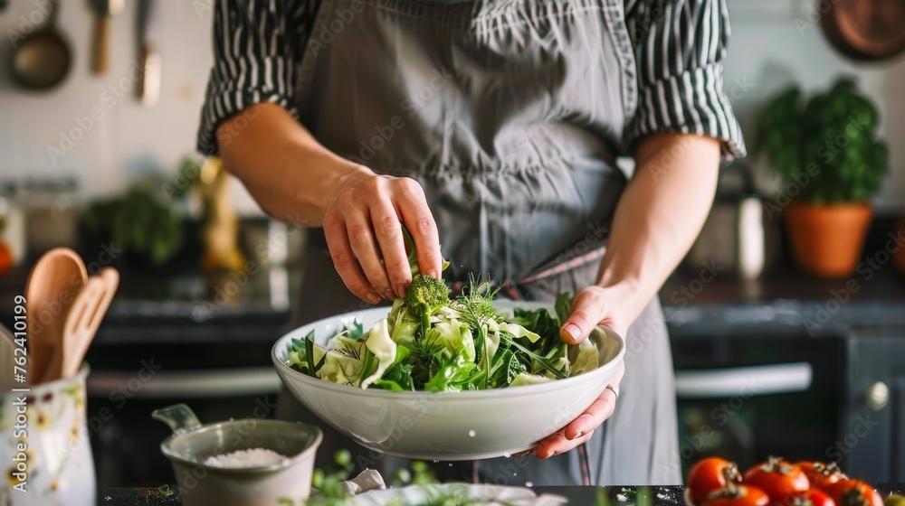 A young woman in a gray apron sipes a salad of Chinese cabbage - obrazy, fototapety, plakaty 