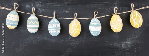 Happy Easter holiday decoration celebration concept greeting card - Pastel painted easter eggs, hanging on a string, on chalkboard wall texture background