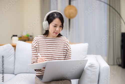 Woman study on laptop computer and jotting note at home