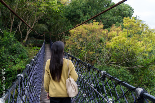 Woman walk along the suspension bridge in the forest