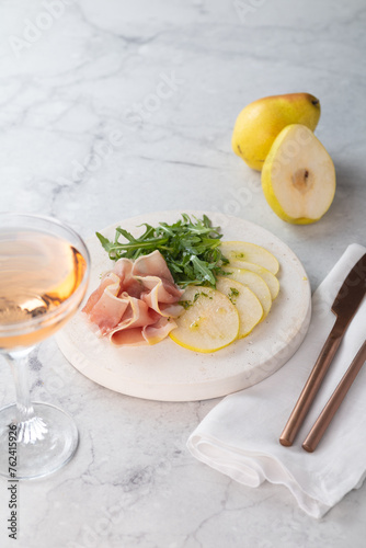 Summer pear salad with prosciutto  arugula on light great marble background. Healthy diet concept. Italian cuisine. Vertical