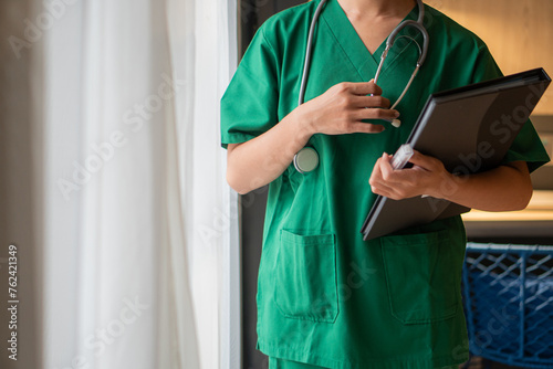 Female doctor with lab coat in her office holding a clipboard with medical records