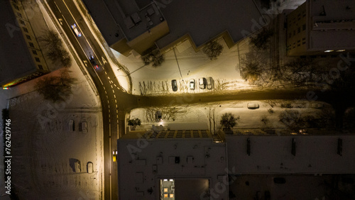 Drone photography of a street between buildings covered by snow during winter night