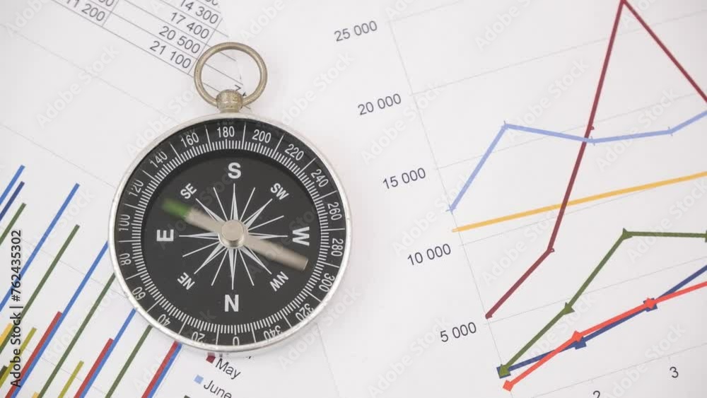 Round compass with rotating pointer on financial charts and graphs. Round compass with rotating pointer on financial charts and graphs.