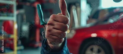 Mechanic showing thumb up gesture while standing with auto mechanic