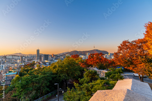 Sunset of Seoul cityscape with high rise office buildings and skyscrapers and cityFortress wall of Heunginjimun with autumn colorful park, Seoul, South Korea in autumn season