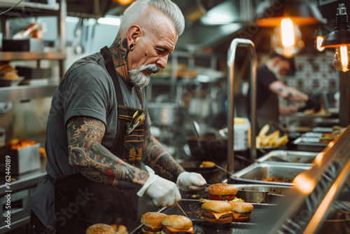 Tattooed chef prepares burgers in a commercial kitchen with intense focus