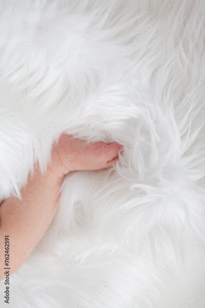 Ilittle baby dressed in a faithful bodysuit is lying on a white plush blunket Ilittle baby dressed in a faithful bodysuit is lying on a white plush blunket