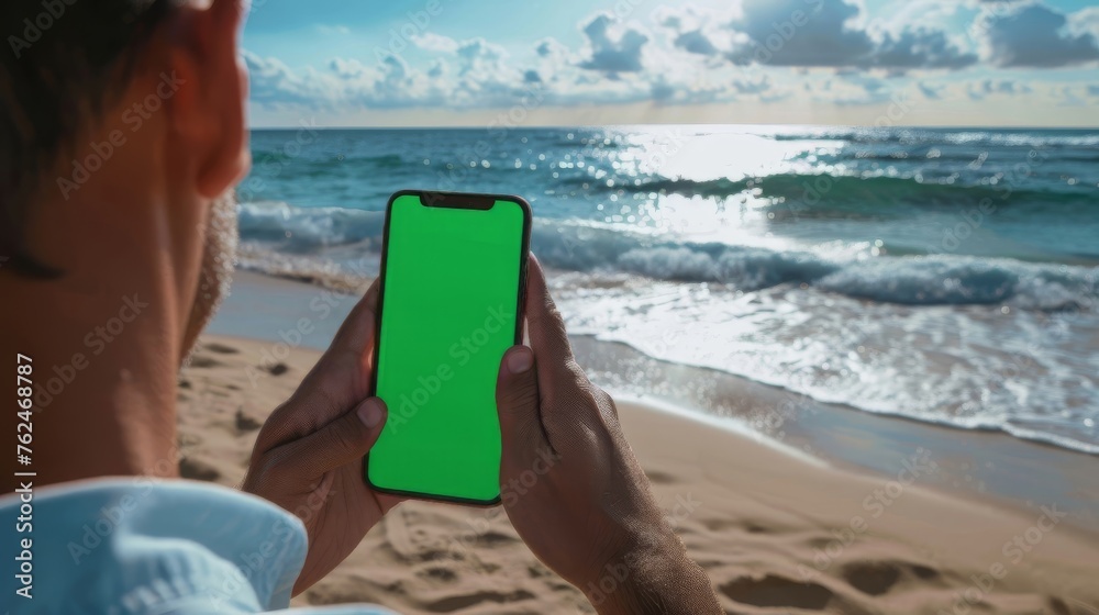 Hand Holding Smartphone with Green Screen on Tropical Beach Backdrop - Ideal for App Mock-ups and Digital Lifestyle