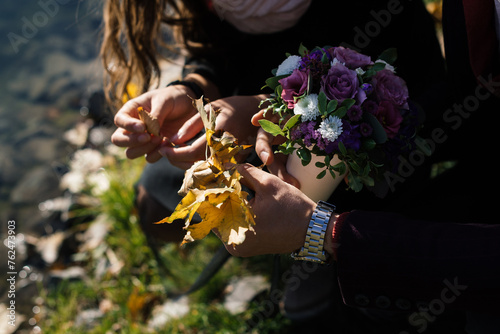 beautiful autumn bouquet and yellow leaves in the hands of a man and woman in the rays of sunlight