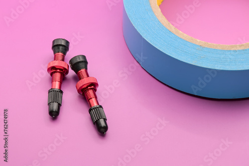anodized red tubeless presta valves with tube less rim tape on plain background (cut out, isolated on magenta pink red) valve photo