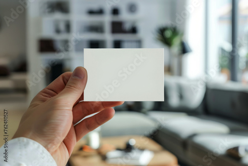 Hand holding a blank business card in a dynamic office setting, representing professional exchange and networking