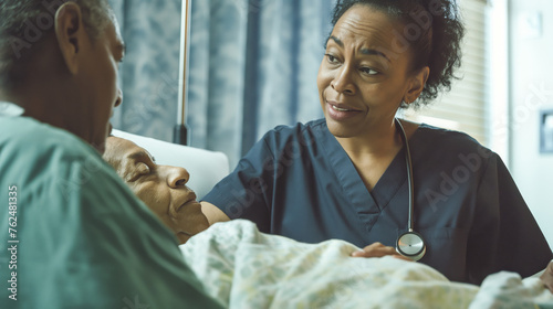 A black nurse in scrubs talking to an elderly patient lying in the bed photo