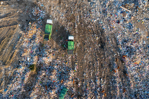 Aerial view of garbage truck unload pile of waste at landfill with cows. Dump of unsorted waste garbage pile in trash dump. Environmental pollution and ecological disaster. View from drone